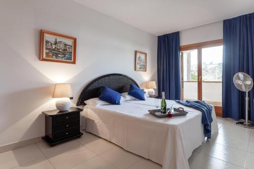 a bedroom with a bed with blue pillows and a window at La marinera Beach House in Platja  d'Aro