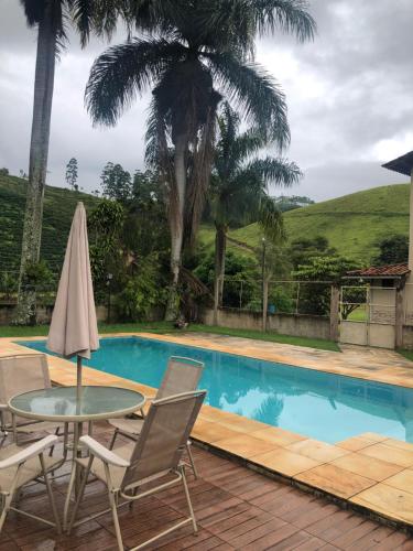 une terrasse avec une table, des chaises et une piscine dans l'établissement Pousada Viva, à Ibitirama