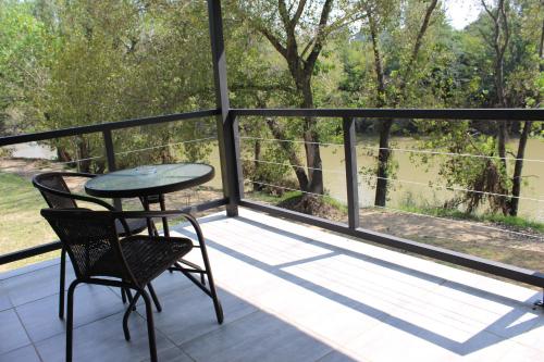 a table and chairs on a balcony with a view at At the River Guest House in Kroonstad