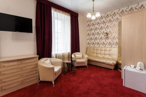 a living room with a couch and chairs and a television at ART Hotel in Kirov