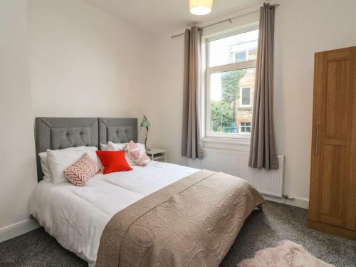 Schlafzimmer mit einem Bett mit roten Kissen und einem Fenster in der Unterkunft Annielea is a cosy 3 bed Cottage in Helensburgh in Helensburgh