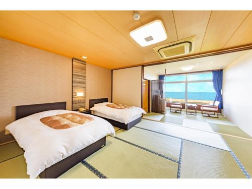two beds in a room with a view of the ocean at Umino Hotel Hajime in Beppu