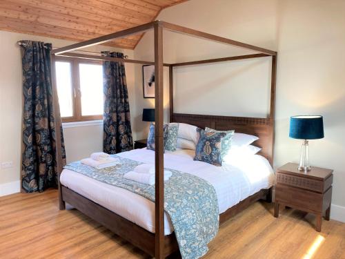 um quarto com uma cama de dossel e uma janela em Pheasant Lodge with Hot Tub em Forgandenny