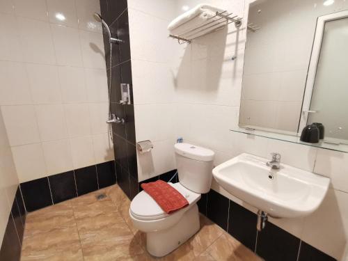 a bathroom with a toilet and a sink and a mirror at Marilyn Hotel Serpong in Serpong