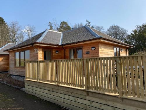 a wooden house with a wooden fence at Pheasant Lodge with Hot Tub in Forgandenny