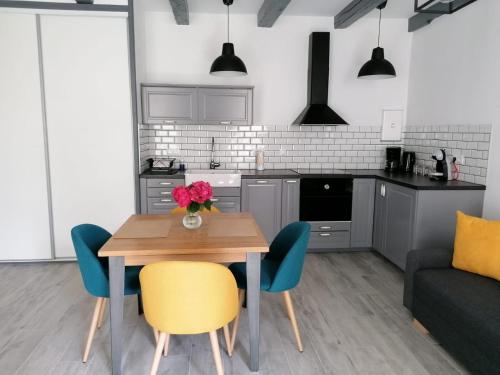 cocina con mesa de madera y sillas azules en residence fleurie rdc, en Saint-Malo