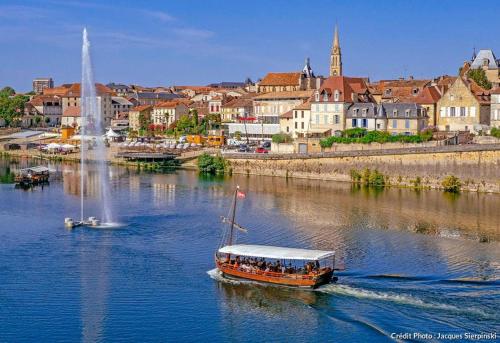 a boat on a river with a city in the background at Superbe appartement tout équipé proche Hypercentre in Bergerac