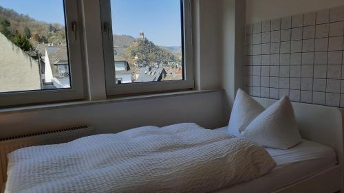 a bedroom with a white bed with two windows at Pension Schneider in Cochem