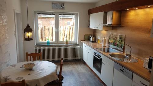 een keuken met een tafel, een wastafel en een raam bij Gaestehaus-Zur-alten-Post-Wohnung-Sued in Dornum