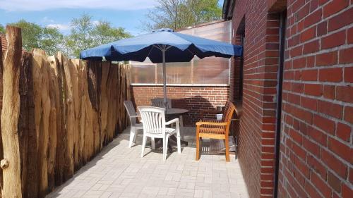 een patio met een tafel en stoelen en een parasol bij Gaestehaus-Zur-alten-Post-Wohnung-Sued in Dornum