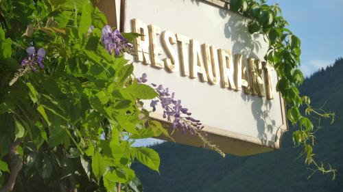 a sign for a restaurant with a bunch of purple flowers at Hotel Schön in Aßmannshausen