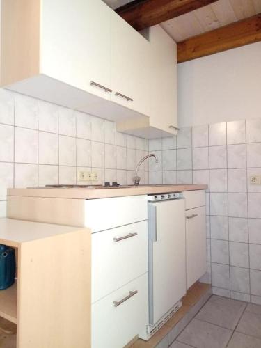 una cocina con armarios blancos y fregadero en 25qm großes Ferienhäuschen " Der Hengstall" auf unserem Reiterhof en Birkenbeul