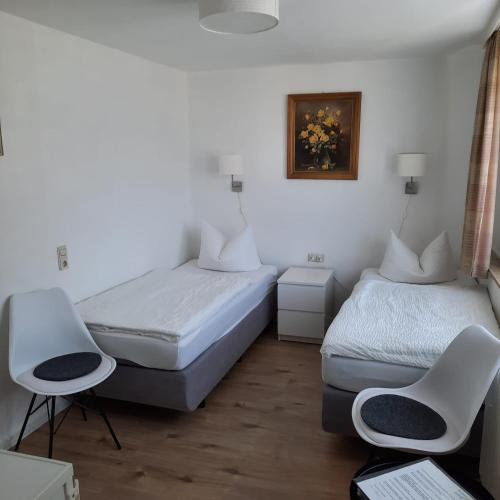 a room with two beds and a chair in it at Pension Schneider in Cochem