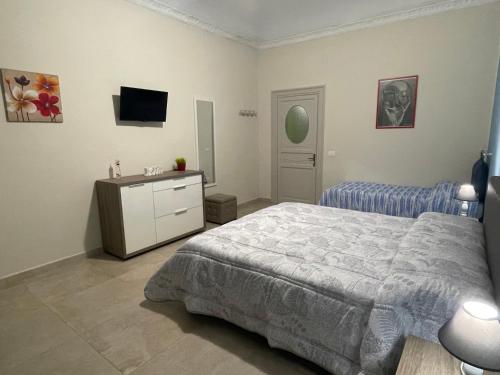 een slaapkamer met een bed, een ladekast en een televisie bij Porte Maqueda in Palermo