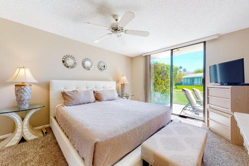 a bedroom with a bed and a tv and a window at Palm Springs Condo, Sunrise Villas in Palm Springs