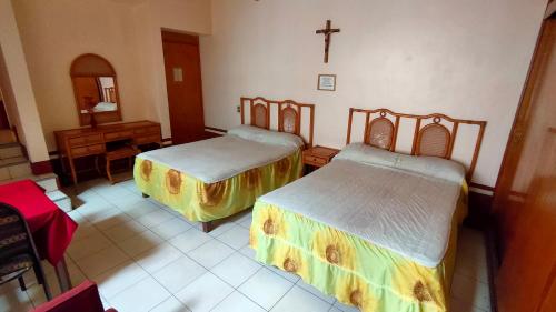 a room with two beds and a cross on the wall at OYO Posada Santa Cecilia, Jerez Zacatecas in Jerez de García Salinas