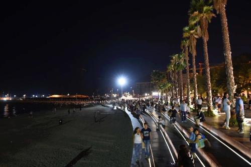 una folla di persone che camminano lungo una spiaggia di notte di Tasso Apartment a Salerno