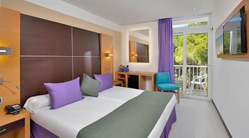 1 dormitorio con 1 cama grande con almohadas moradas y grises en Hotel Isla de Cabrera, en Colonia de Sant Jordi