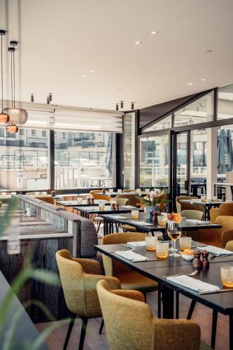 a restaurant with tables and chairs and windows at Casino Hotel in Koksijde