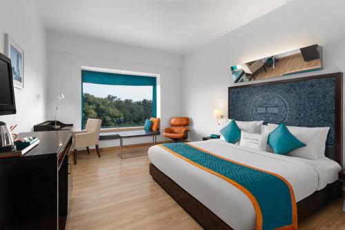a hotel room with a large bed and a desk at Golden Tulip City Centre Gurgaon in Gurgaon