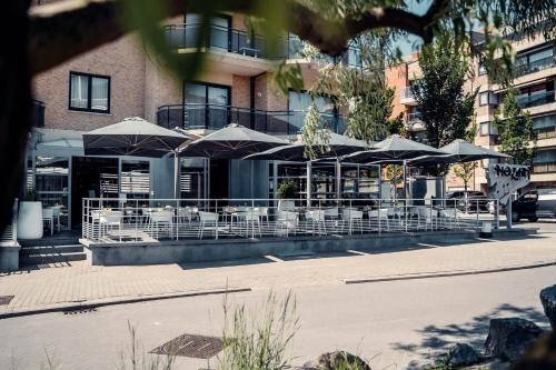a restaurant with tables and umbrellas in front of a building at Casino Hotel in Koksijde