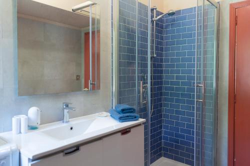 a bathroom with a sink and a shower with blue tiles at Beach House Blue Holiday in Letojanni