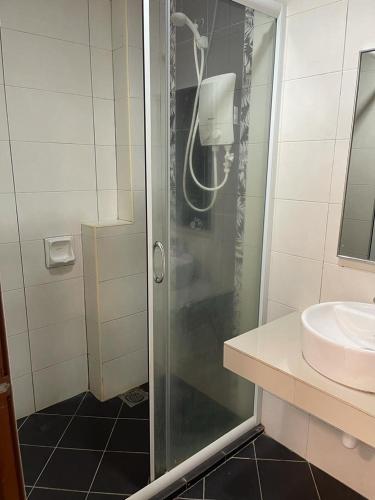 eine Dusche mit Glastür neben einem Waschbecken in der Unterkunft Marina heights hotel residence in Lumut
