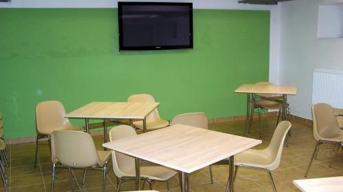une salle de classe avec des tables et des chaises et une télévision sur un mur vert dans l'établissement Ubytovna Marie, à Olomouc