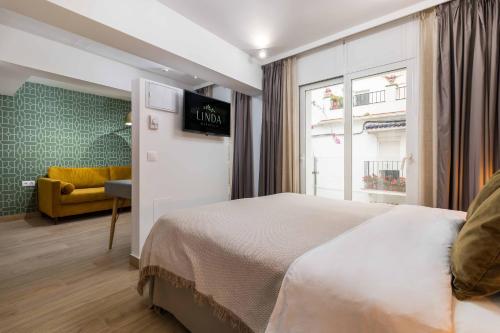 a hotel room with a bed and a yellow couch at Linda Boutique Hotel in Marbella