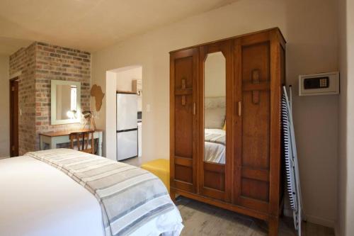 a bedroom with a bed and a wooden cabinet at Viettz Suite in Stellenbosch