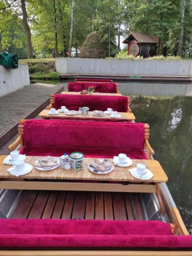 trois jeux de tables avec des assiettes de nourriture sur un bateau dans l'établissement Spreewaldpension Zickert, à Lübben