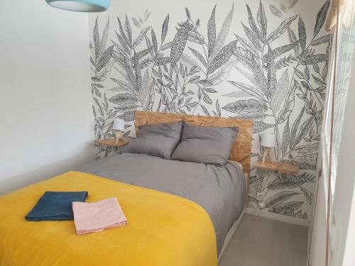 1 dormitorio con cama amarilla y papel pintado tropical en LA PIERRINA - Chamois - Appart 3 étoiles, en Aix-les-Bains