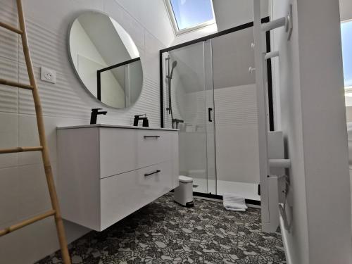ein weißes Badezimmer mit einem Waschbecken und einem Spiegel in der Unterkunft Une escale en Berry in Foëcy