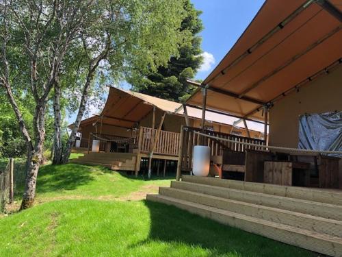 ein Haus mit einer Veranda und einer Treppe im Hof in der Unterkunft AZUR Camping Schwäbische Alb in Sonnenbühl