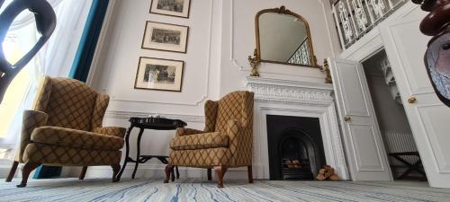 a living room with two chairs and a fireplace at Commodore Hotel in London
