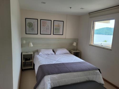 - une chambre avec un grand lit et une fenêtre dans l'établissement Apart Hotel Mont Blanc Itacuruçá, à Mangaratiba