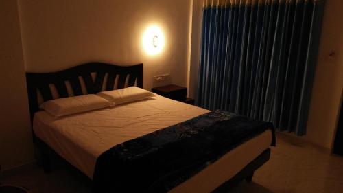 1 dormitorio con 1 cama y una ventana con cortinas en VIBGYOR HOMES, en Munnar