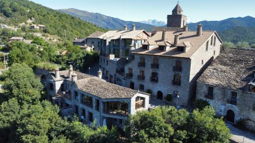 un antiguo edificio en una ciudad con montañas en el fondo en Hotel Rural LAbadia de Sieste en Sieste