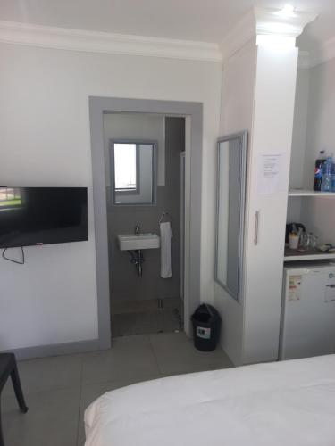 ein weißes Schlafzimmer mit einem Waschbecken und einem Badezimmer in der Unterkunft Triple9 Hatfield Guesthouse in Pretoria
