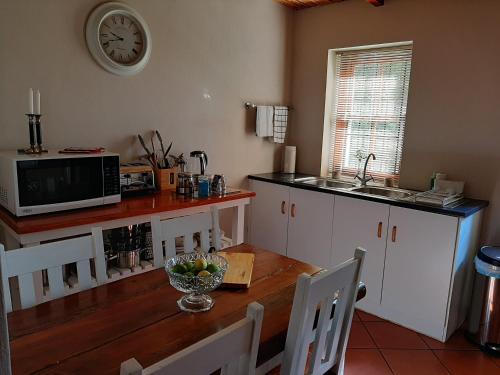 a kitchen with a wooden table and a clock on the wall at Nieuwedrift accommodation in Piketberg