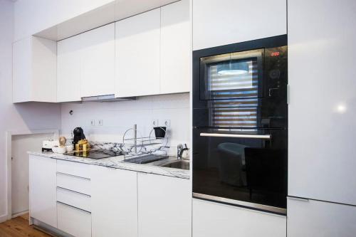 cocina con armarios blancos y microondas negro en Lighthouse Apartment, en Oporto