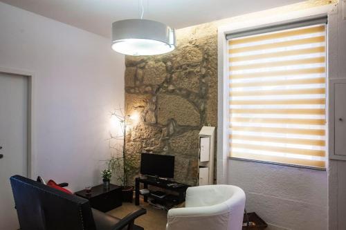 a living room with a stone wall and a television at Lighthouse Apartment in Porto