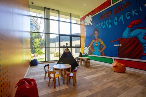 a room with a table and chairs and a superhero wall at Somerset Westview Nairobi in Nairobi