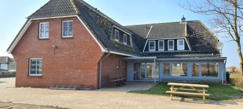 a red brick house with a wooden bench in front of it at Deichhus Nordseeliebe direkt am Deich - Nordsee - Dagebüll - Am Vogelreservat in Dagebüll