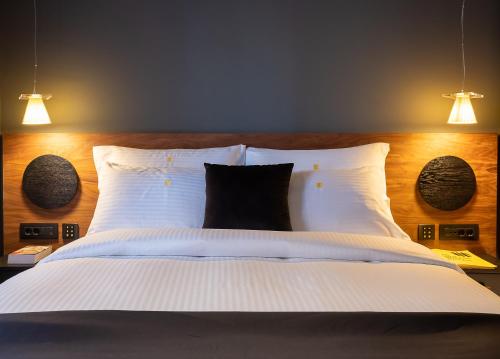 a bedroom with a bed with white sheets and two lights at 3 Pines Design Living in Heraklio Town
