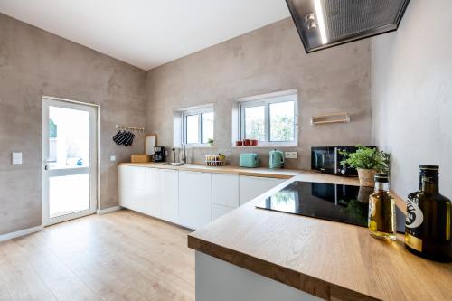 a large kitchen with white cabinets and a large window at Fortaleza sea view Villa Miramar - Apartment with private pool in Budens