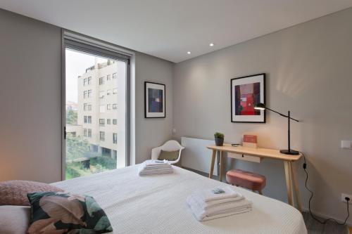 een slaapkamer met een bed, een bureau en een raam bij Balconies of Cedofeita & Garage in Porto
