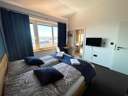 a bedroom with a bed with blue pillows and a window at Penzion Nad Lávkou in Uherský Brod