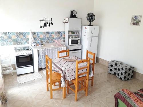 a kitchen with a table and a white refrigerator at Edícula - Casa de hospedes - em Cananeia SP com ar condicionado in Cananéia