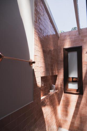 a bathroom with a mirror and a brick wall at Øko Villa in Juquei
